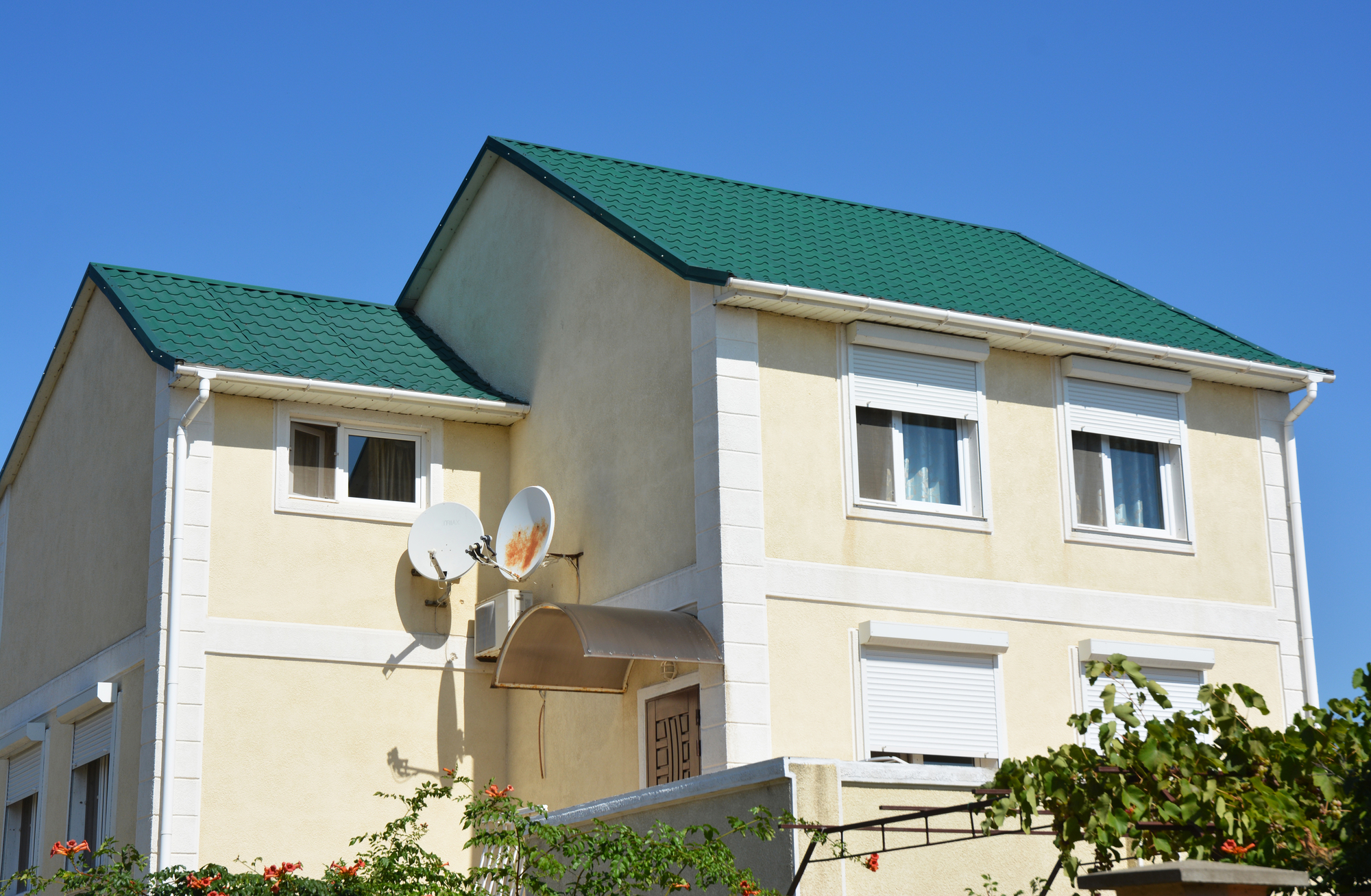 Rodinný dom so zelenou strechou a bielymi vonkajšími žalúziami