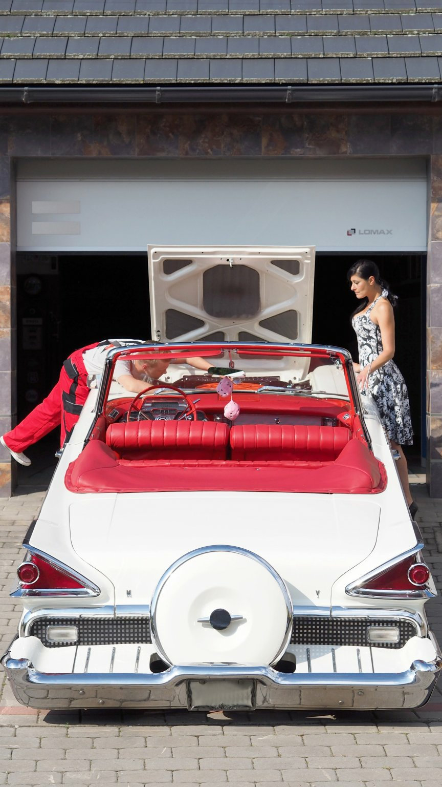 Bielo-červený veterán pred otvorenou garážou