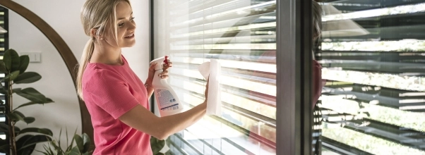 Žena umýva papierovou utierkou a sprejom veľké francúzske okná 