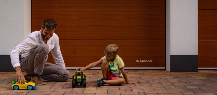 Otec a syn s hračkami pred garážovou bránou LOMAX